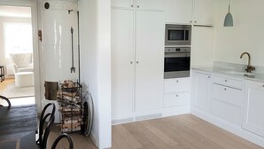 Eine Küche mit weißen Schränken, einem eingebauten Backofen, einer Mikrowelle und einer Pendelleuchte.