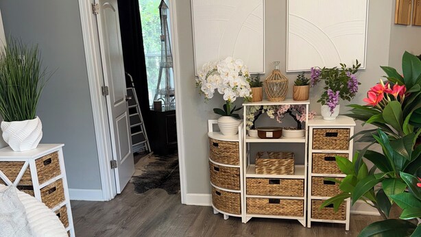 A room with a wooden floor, white furniture, wicker baskets, and potted plants. -  The Langley Luxe Modern style unit (Chicago)