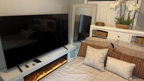 A bedroom with a TV, fireplace, bed, and decorative items. -  The Langley Luxe Modern style unit (Chicago)