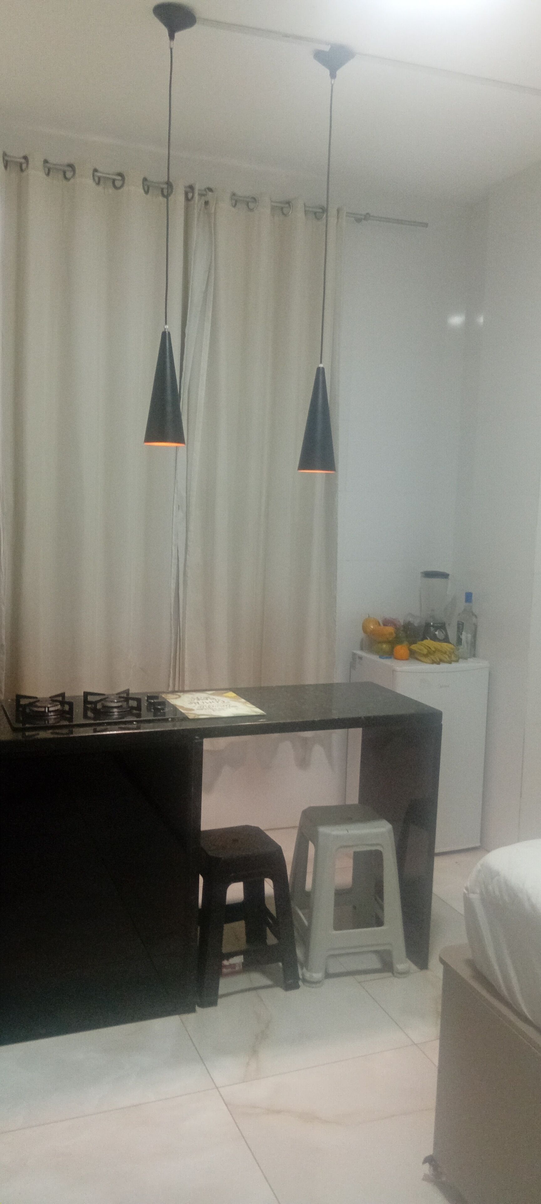 A kitchen with a gas stove, a black countertop, a white refrigerator, and a small stool.