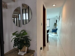 A hallway with a plant, a mirror, and a dining area in the background. - Marina del Sol con Vista al Mar | by GPS (Mazatlán)