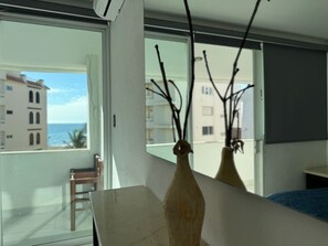 A room with a large window, a wooden table, and two vases with branches. - Marina del Sol con Vista al Mar | by GPS (Mazatlán)