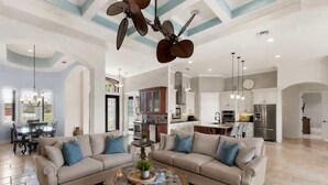 A spacious living room with a sectional sofa, a coffee table, and a ceiling fan. - Marco Island Bayfront Pool & Spa (Marco Island)