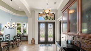 A spacious kitchen with a black countertop, a hanging light fixture, and a decorative door with glass panels. - Marco Island Bayfront Pool & Spa (Marco Island)