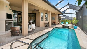 A pool area with a covered patio, seating, and a fireplace. - Marco Island Bayfront Pool & Spa (Marco Island)