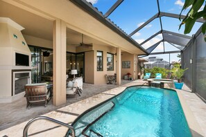 Ein Poolbereich mit überdachter Terrasse, Sitzgelegenheiten und Kamin.