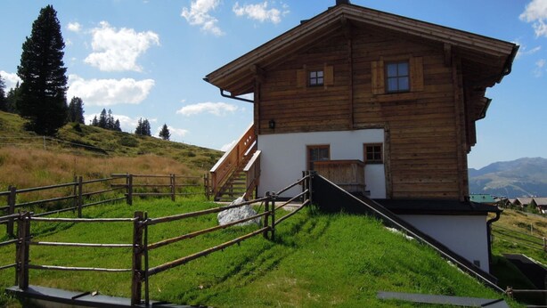 A wooden chalet with a sloped roof, a staircase leading to the entrance, and a view of the surrounding hills. - Ski Lodge in Krimml With Swimming Pool (Krimml)