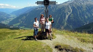 Un groupe de personnes se tient sur un sentier de montagne, avec une structure en forme de croix en arrière-plan.