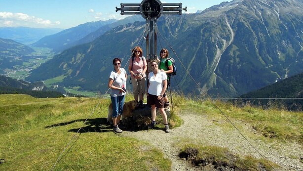 A group of people standing on a mountain trail with a cross structure in the background. - Ski Lodge in Krimml With Swimming Pool (Krimml)