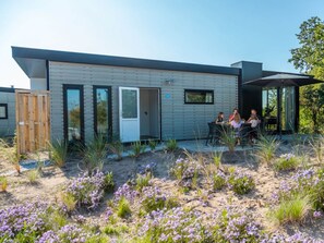 Ein modernes Haus mit einer Terrasse, auf der Leute sitzen.