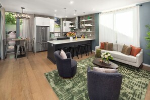 Una cocina moderna con una isla central, taburetes de bar y un comedor con mesa y sillas.