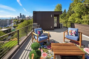 Une terrasse sur le toit avec deux chaises, une petite table et une vue sur le panorama de la ville.