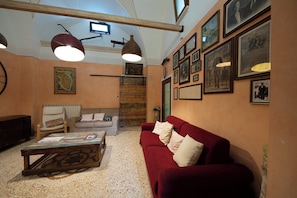 A living room with a red sofa, a wooden coffee table, a white armchair, and a fireplace.