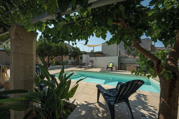 Ein Pool mit Liegestühlen, einer Pergola und einer Säule aus Stein.