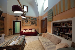 A cozy living room with a red sofa, a wooden coffee table, and a bookshelf filled with books.