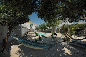 A hammock, a pool, and potted plants in a courtyard.
