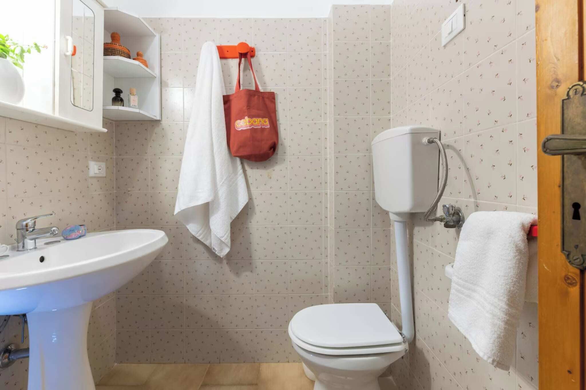 Une salle de bain avec un lavabo blanc, des toilettes et une serviette accrochée au mur.