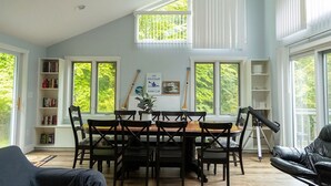 Uma área de refeições com uma mesa, cadeiras, uma estante de livros e um telescópio.