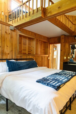 Ein Zimmer mit Holzboden, einem Bett, einem Schreibtisch und einem Fenster.