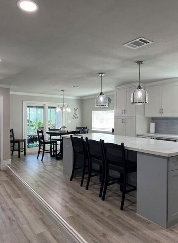 A modern kitchen with a central island, pendant lighting, and a view to the outdoors. - Coastal Gem with River Views (Matagorda)