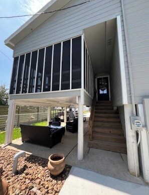 A two-story house with a covered patio area, a staircase, and outdoor furniture. - Coastal Gem with River Views (Matagorda)