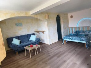Une pièce de taille modeste, comprenant un canapé, une petite table et un lit.