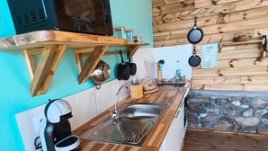 A kitchen with a wooden countertop, a sink, a microwave, and hanging pans. - Caribbean Beach Studios. Ti Colibri Studio near the beaches in Ferry-Deshaies (Deshaies)