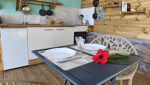 A kitchen with white cabinets, a wooden countertop, and a dining area with a table set for two. - Caribbean Beach Studios. Ti Colibri Studio near the beaches in Ferry-Deshaies (Deshaies)