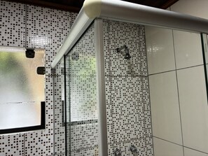 Eine Dusche mit Glastür und gefliestem Wandbereich mit quadratischem Muster.