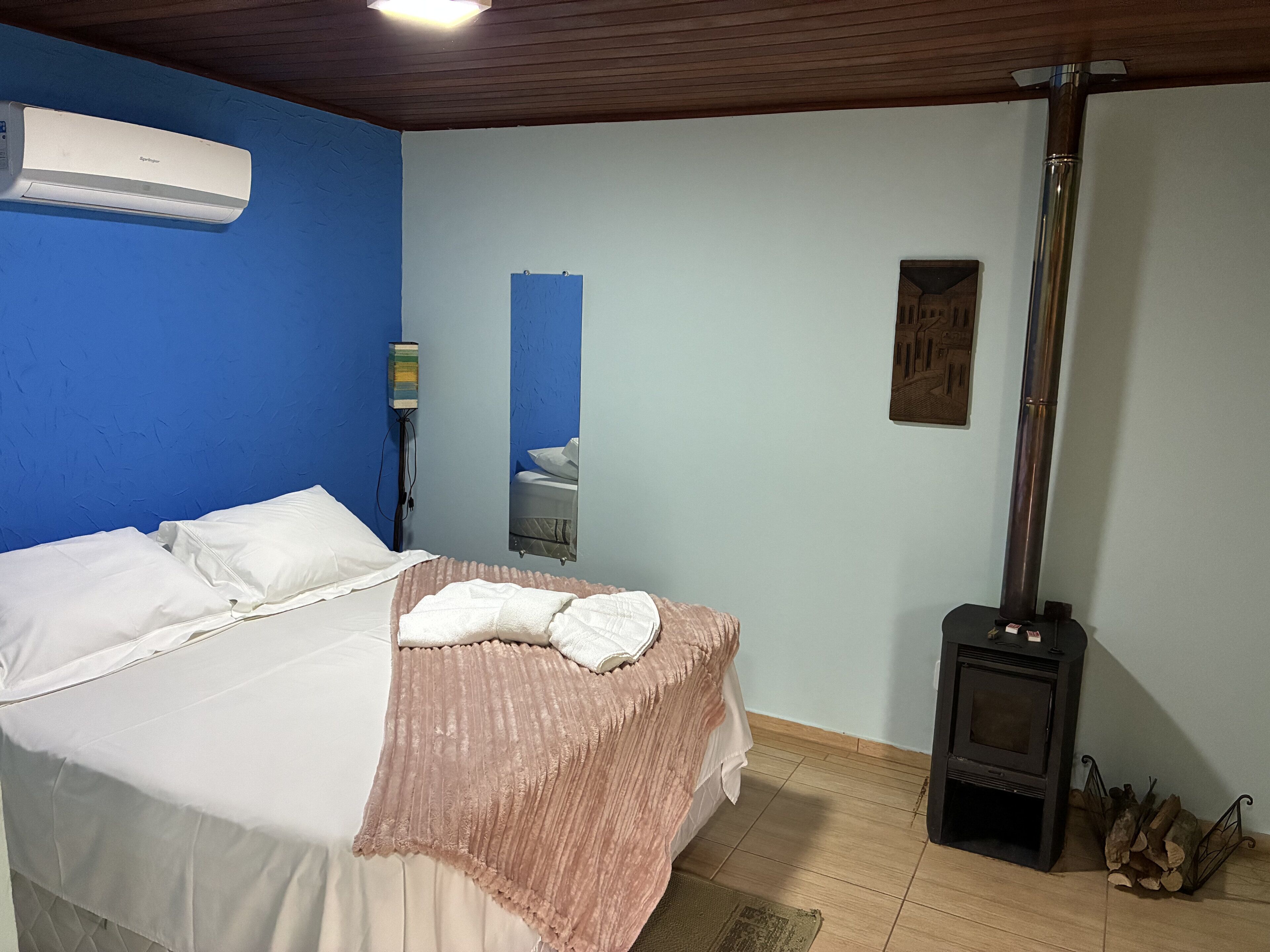 Ein Schlafzimmer mit einem Bett, einem Spiegel, einem Wandheizkörper und einem Kaminofen.