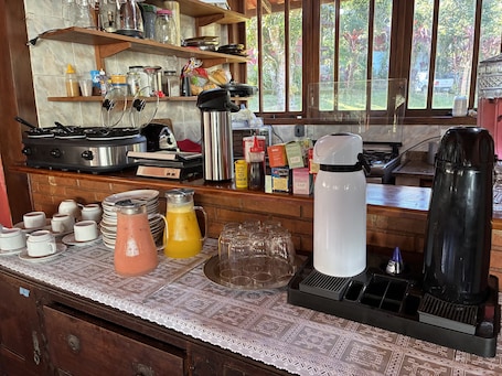 A kitchen with a stove, coffee maker, and various kitchen items on shelves.. Alta Colina Chalés