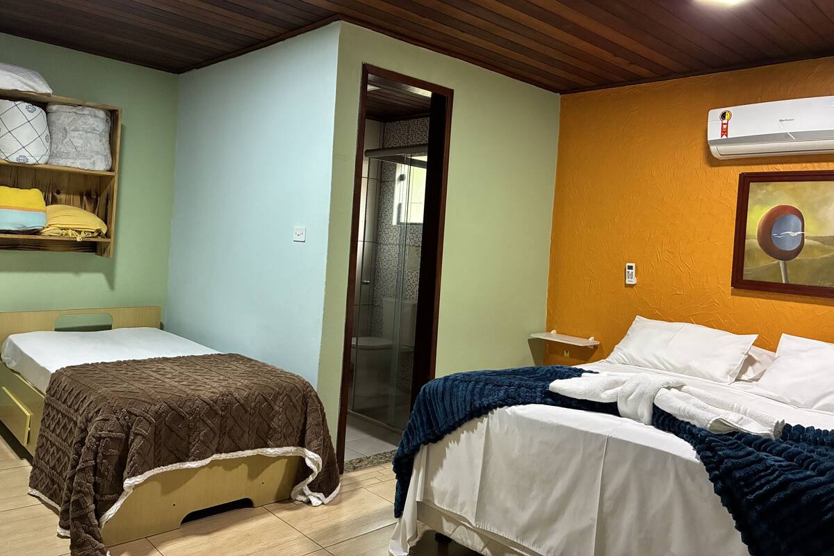 Una habitación con dos camas, techo de madera, aire acondicionado y un cuadro enmarcado en la pared.