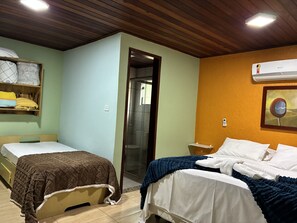 Ein Zimmer mit zwei Betten, einer Holzbalkendecke, einer Klimaanlage und einem gerahmten Bild an der Wand.
