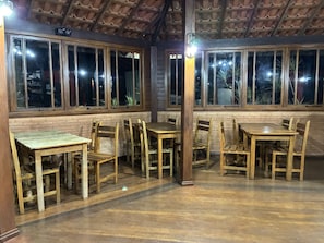 Un restaurant avec des tables et des chaises en bois, de grandes fenĂȘtres et un mur en briques.