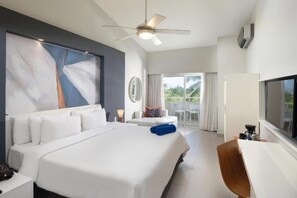 A modern hotel room with a large bed, a desk, a ceiling fan, and a balcony with a view.