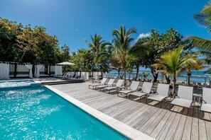 A poolside area with lounge chairs, a wooden deck, and a view of the ocean. - Emotions by Hodelpa - Juan Dolio (Juan Dolio)