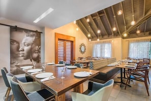 A dining area with a long table set for multiple people, a wooden ceiling, and a large framed picture on the wall. - Emotions by Hodelpa - Juan Dolio (Juan Dolio)