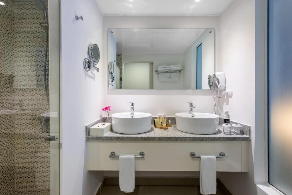 Une salle de bain moderne avec deux lavabos, un grand miroir et une douche à l’italienne.