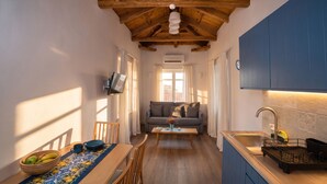Cocina compacta con techo de madera, lavamanos integrado y comedor con mesa para dos.