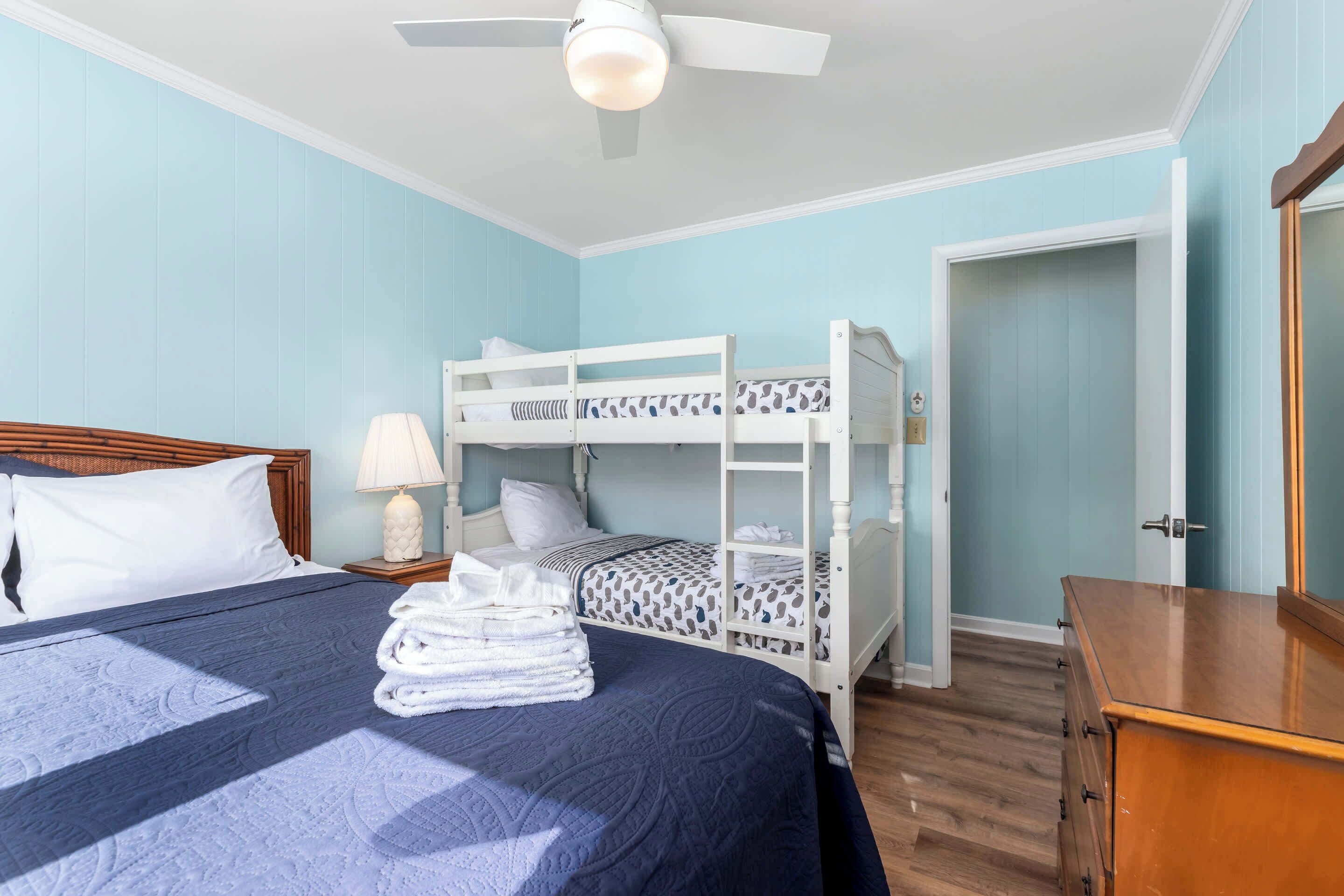Ein Zimmer mit Etagenbetten, einer Holzkammer und einem Deckenventilator, sowie einer Tür zu einem anderen Raum.