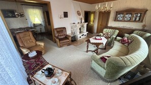 A traditional living room with leather armchairs, a green sofa, a fireplace, and a dining area with a table set for tea.