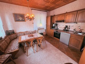 Una cocina acogedora con armarios de madera, una mesa de comedor con sillas y un horno empotrado.