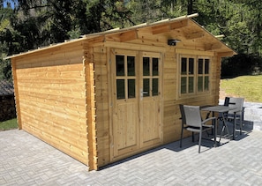 A wooden cabin with a porch, a table, and chairs.