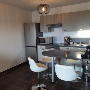 Eine moderne Küche mit Kühlschrank, Mikrowelle, Kaffeemaschine und Barhocker.