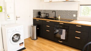 Une cuisine de taille réduite équipée d’un lave-linge, d’une poubelle et d’un lave-vaisselle.
