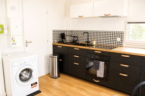 Una cocina compacta con lavadora, un bote de basura y lavavajillas.