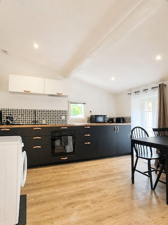 A modern kitchen with a central island, built-in appliances, and a dining area with a table and chairs.. Charming 4-person studio 5 minutes from the citadel