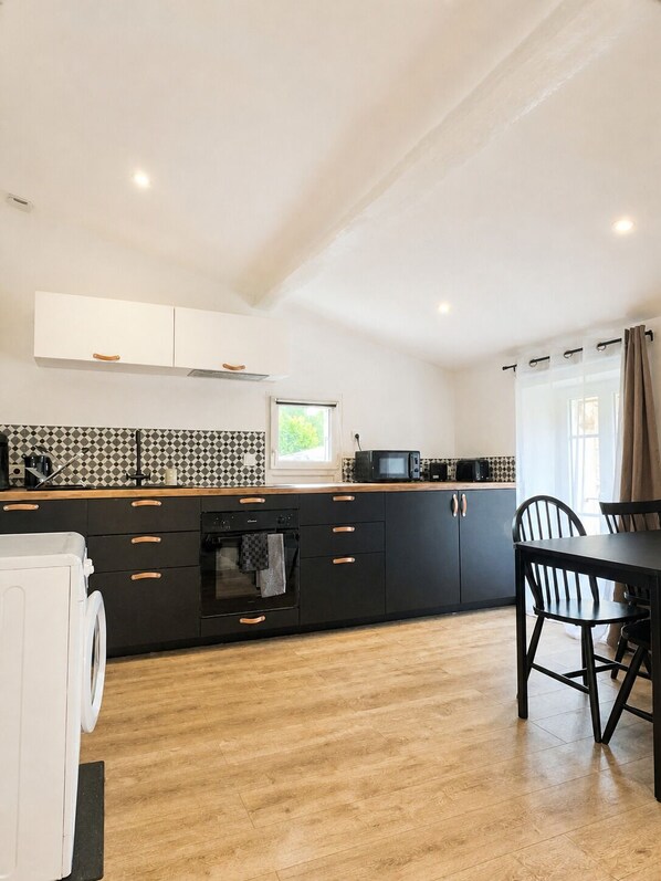 Una cocina moderna con una isla central, electrodomésticos integrados y un comedor con mesa y sillas.