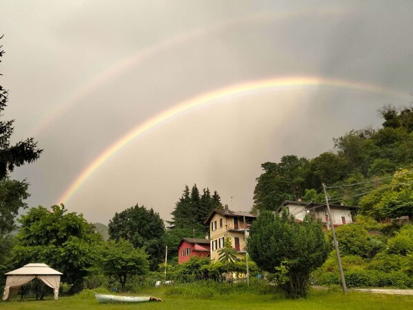 A house with a red roof, surrounded by greenery and a white tent. - Natura tra bosco e lago (Castelveccana)