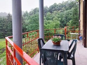 A balcony with a table, chairs, and a potted plant.